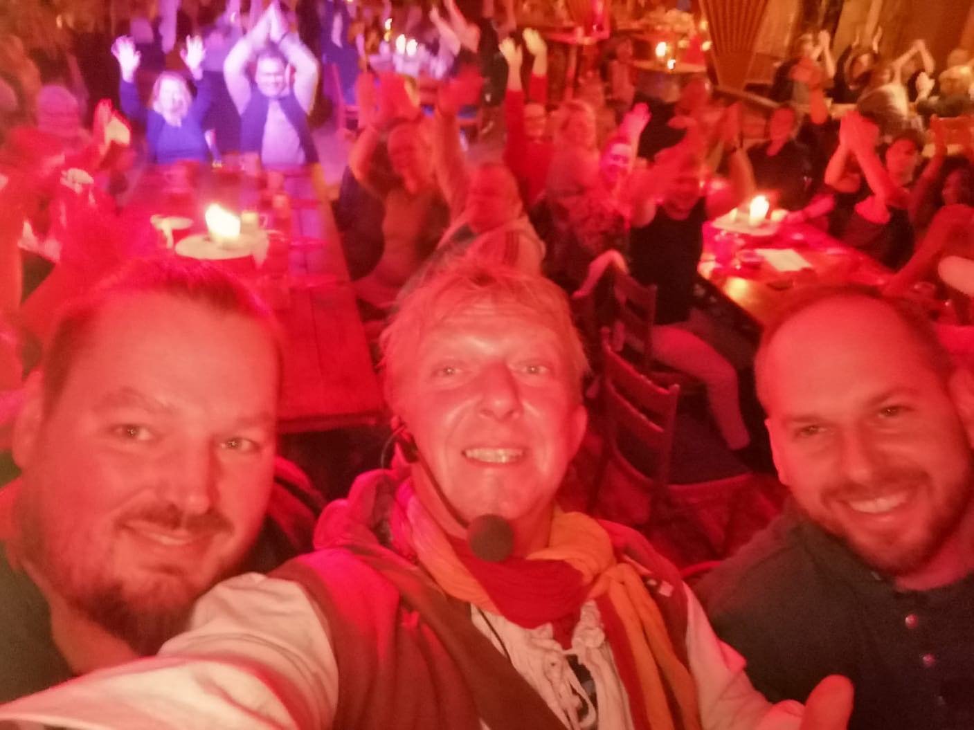 Drei Musiker vor einem jubelnden Publikum in rotem Bühnenlicht